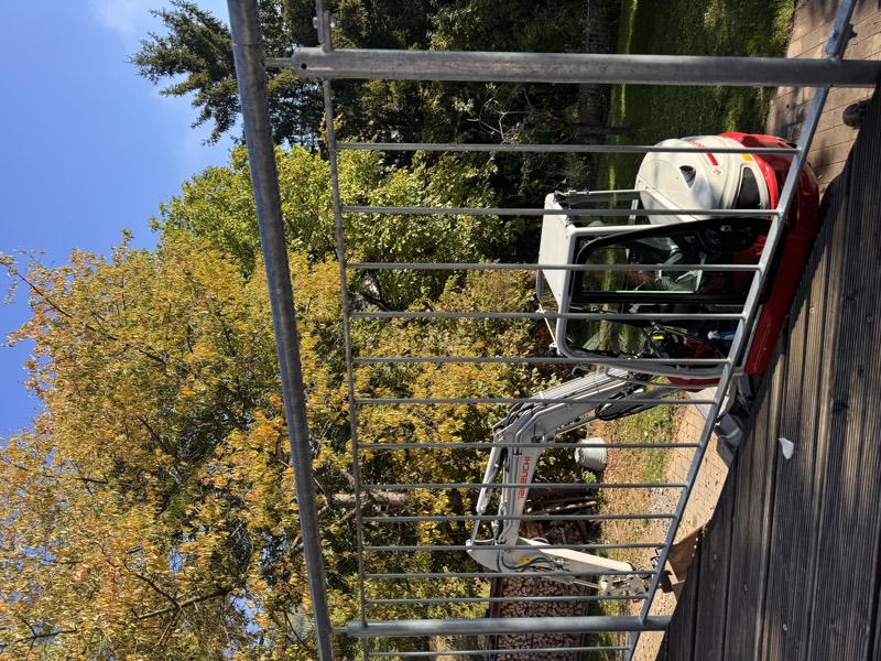 Verzinktes Geländer nach Maß an einer Holzterrasse, dahinter steht der Minibagger.